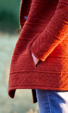 a close up of a person wearing an orange sweater and jeans with her hands in their pockets