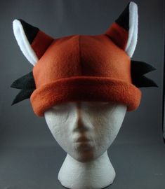 a white mannequin head wearing an orange and black hat with horns on it