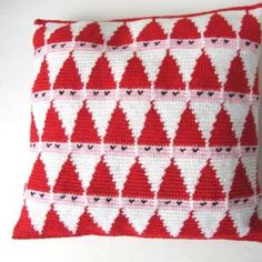 a red and white knitted pillow with trees on it