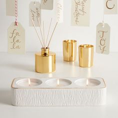 three candles and some tags on a white table