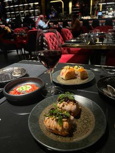 two plates with food and a glass of wine on a table in a fancy restaurant