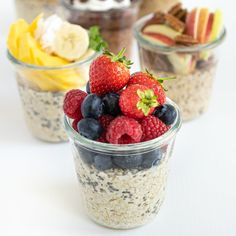 three cups filled with fruit and granola on top of a white table next to bananas