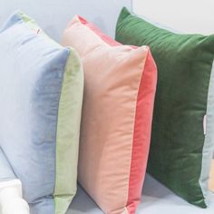 three different colored pillows sitting on top of a couch