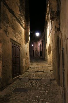 an alley way with cobblestones and stone buildings at night