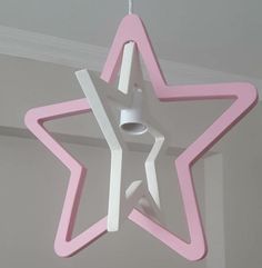 a pink and white star shaped light fixture hanging from the ceiling in a child's room