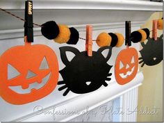 halloween decorations are hanging on the mantle with cat heads and pumpkins attached to them