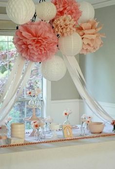 a table topped with lots of pink and white paper flowers on top of a table