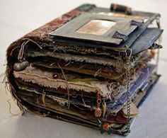 a stack of old books sitting on top of a white table covered in papers and chains