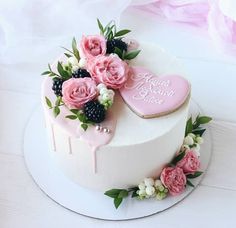 a heart shaped cake with flowers and berries on the top is sitting on a table