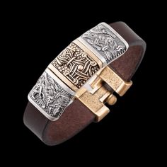 a brown leather bracelet with two gold and silver metal clasps on top of it