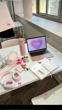 an open laptop computer sitting on top of a white table next to a pink object