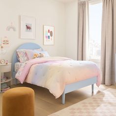 a child's bedroom with pink and blue bedding, white walls and flooring