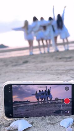 a cell phone sitting on top of a sandy beach next to two white seagulls