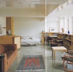 a living room filled with lots of furniture and bookshelves next to a window