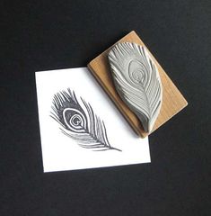 a rubber stamp with a feather on it and a piece of paper next to it