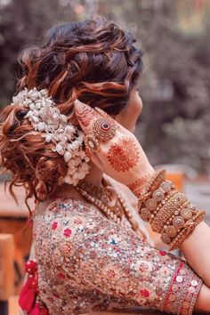 a woman with henna on her head and hands behind her ear looking at something