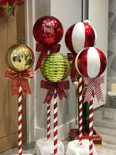 three red and white candy canes are on display in front of a door with christmas decorations