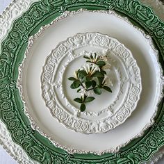 a green and white plate with flowers on the center, sitting on a table cloth