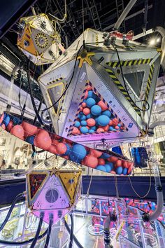 several colorful kites hanging from the ceiling in an indoor shopping mall with lights and decorations