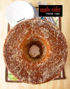 an apple cider pound cake with powdered sugar in the center on a wooden table