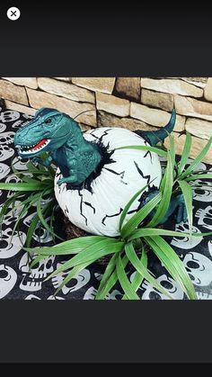 a fake t - rex sitting on top of an egg in the middle of some plants