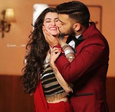 a man kissing a woman on the cheek in front of a red suit and tie