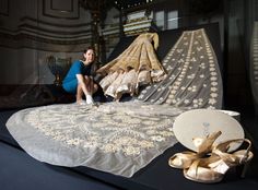 a woman sitting on top of a table next to some cloths and gold shoes