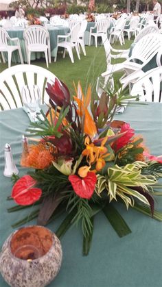 an arrangement of flowers on a table with chairs in the background at a wedding reception