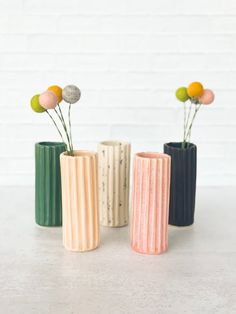 three different colored vases with flowers in them