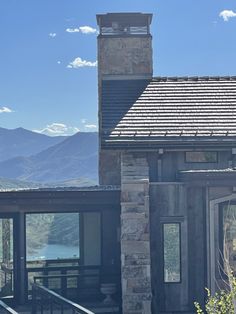 a stone building with a clock tower on the top of it's roof and mountains in the background