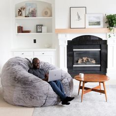 a man sitting on a bean bag chair using a laptop computer in his living room