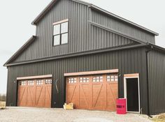 two large garages with doors open in front of a barn