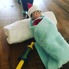 an elf laying on top of a blue towel next to a yellow and black toothbrush