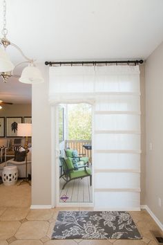 an open door leading to a living room with a green chair and rug on the floor