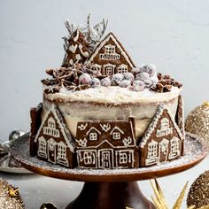 there is a cake decorated with gingerbread houses on the plate and decorations around it