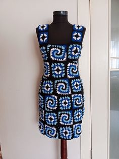 a dress on a mannequin in front of a white door with a black and blue pattern