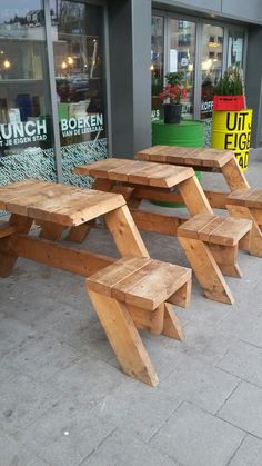 three wooden benches sitting on the side of a street next to a store front window