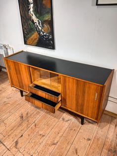 an art deco sideboard with two drawers and a painting on the wall behind it