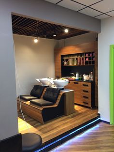 a salon with black leather chairs and wooden flooring in front of a book shelf