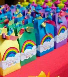 there are many colorful candy boxes on the table with ribbons around them and rainbow decorations