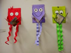 three different colored paper monsters hanging on the wall