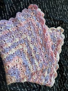 two crocheted dishcloths sitting on top of a black cloth covered table