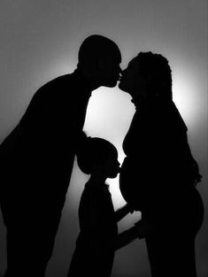 a man and woman kissing in front of the sun with their shadow on the wall