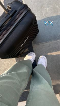 a person standing next to a piece of luggage on the ground with their feet up