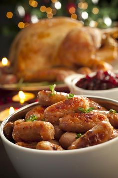 two white bowls filled with chicken and cranberry sauce next to a christmas tree