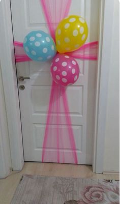 two balloons tied to the front door with pink and blue ribbons on them, one balloon is in the shape of a polka dot