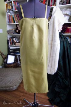 a dress on a mannequin in front of a bookshelf