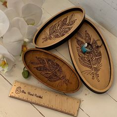 three wooden trays sitting on top of a table next to a ruler and flowers