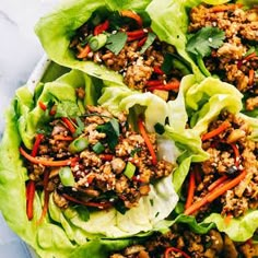 lettuce wraps filled with meat and vegetables on top of a white tablecloth