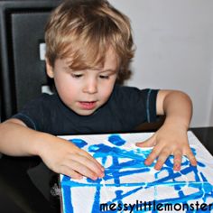 a little boy that is sitting in front of a box with blue paint on it